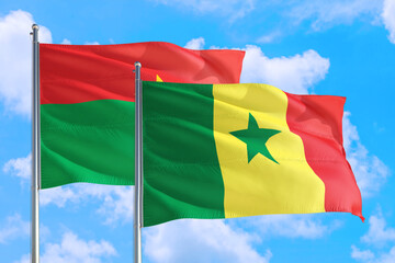 Senegal and Burkina Faso national flag waving in the windy deep blue sky. Diplomacy and international relations concept.