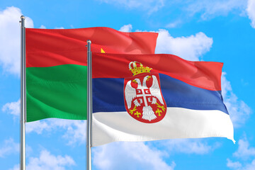 Serbia and Burkina Faso national flag waving in the windy deep blue sky. Diplomacy and international relations concept.