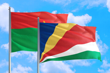 Seychelles and Burkina Faso national flag waving in the windy deep blue sky. Diplomacy and international relations concept.