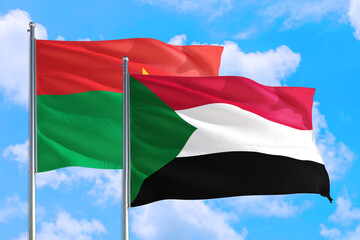 Sudan and Burkina Faso national flag waving in the windy deep blue sky. Diplomacy and international relations concept.