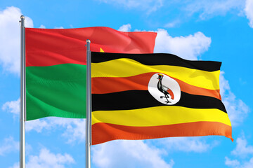 Uganda and Burkina Faso national flag waving in the windy deep blue sky. Diplomacy and international relations concept.