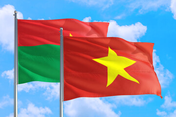 Vietnam and Burkina Faso national flag waving in the windy deep blue sky. Diplomacy and international relations concept.