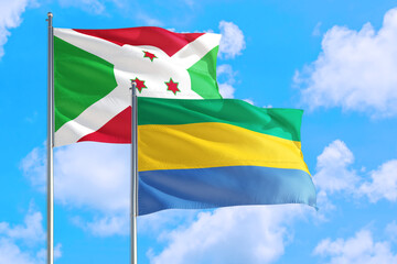 Gabon and Burundi national flag waving in the windy deep blue sky. Diplomacy and international relations concept.