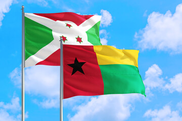 Guinea and Burundi national flag waving in the windy deep blue sky. Diplomacy and international relations concept.