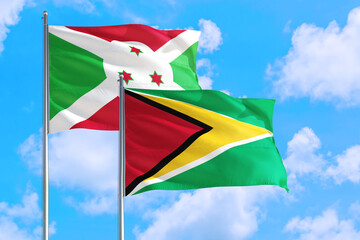 Guyana and Burundi national flag waving in the windy deep blue sky. Diplomacy and international relations concept.