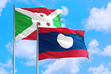 Laos and Burundi national flag waving in the windy deep blue sky. Diplomacy and international relations concept.