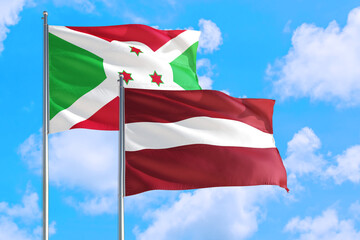 Latvia and Burundi national flag waving in the windy deep blue sky. Diplomacy and international relations concept.