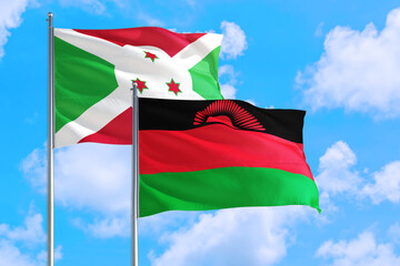 Malawi and Burundi national flag waving in the windy deep blue sky. Diplomacy and international relations concept.