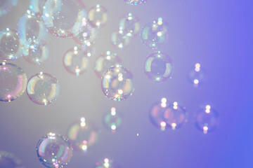 Beatiful shiny clear soap bubbles floating on purple texture background.