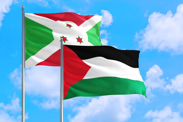 Palestine and Burundi national flag waving in the windy deep blue sky. Diplomacy and international relations concept.
