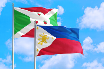 Philippines and Burundi national flag waving in the windy deep blue sky. Diplomacy and international relations concept.