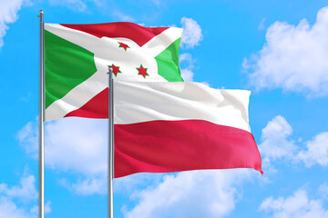 Poland and Burundi national flag waving in the windy deep blue sky. Diplomacy and international relations concept.