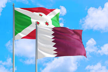 Qatar and Burundi national flag waving in the windy deep blue sky. Diplomacy and international relations concept.