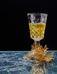 Fototapeta na wymiar Champagne glass with black background and blue marble floor with a golden branch