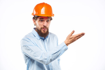 A man in an orange helmet shirt construction industry worked light background