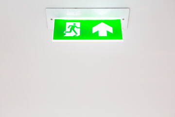 Emergency exit signboard on white ceiling background  and copy space