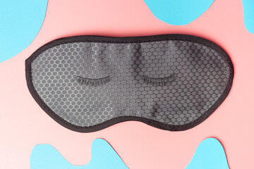 Black false eyelashes on pink and blue background, view from above