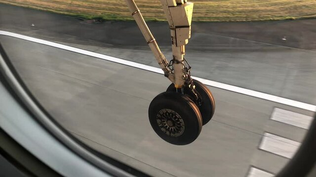 Airplane passenger view of wheels touching down on tarmac as airplane lands