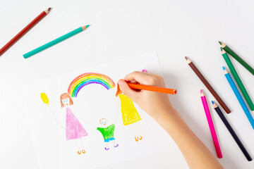 Unrecognizable caucasian boy drawing by coloured pencils his LGBT family. Two mums, son and rainbow. Top view. 