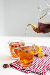 Winter hot tea to strengthen the immune system. Two glass cups in which pour hot tea from the kettle on a white background. Selective focus.