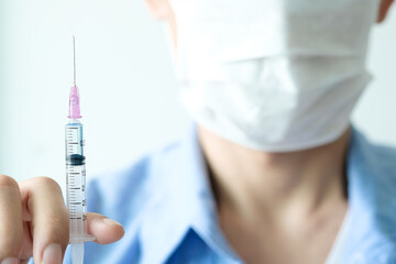doctor's hand holds a syringe and a blue vaccine bottle at the hospital. Health and medical concepts.