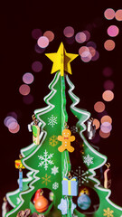 Small miniature christmas tree with cute ornament and dark bokeh background zoom in potrait