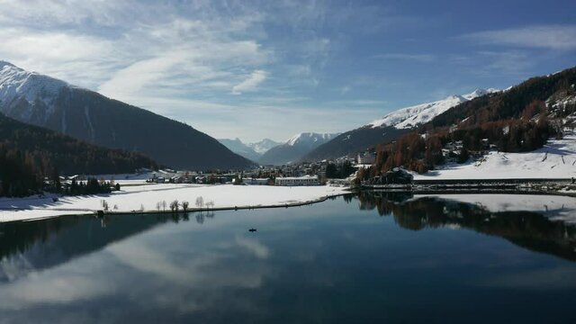 beautiful flight over Davos lake Switzerland with a boat in the reflecting waters