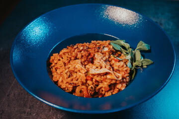 Closeup shot of pilaf with bacon and basil in a blue bowl