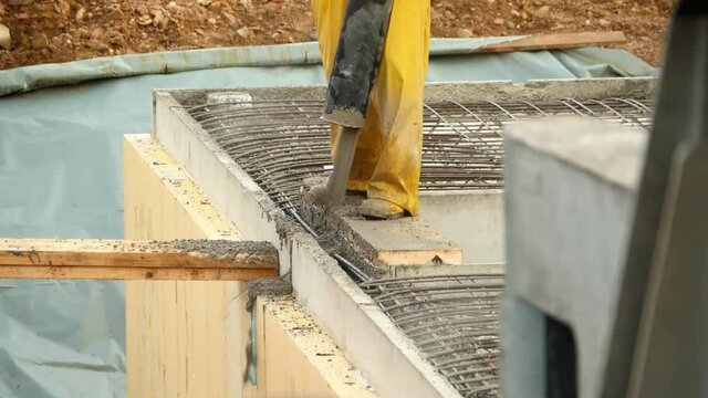 A construction worker fills fresh concrete into a shell wall of a basement