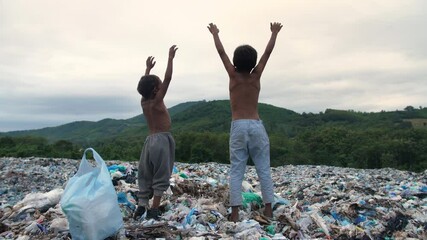 Poverty Boys Standing On Garbage Dump With Arms Raised
