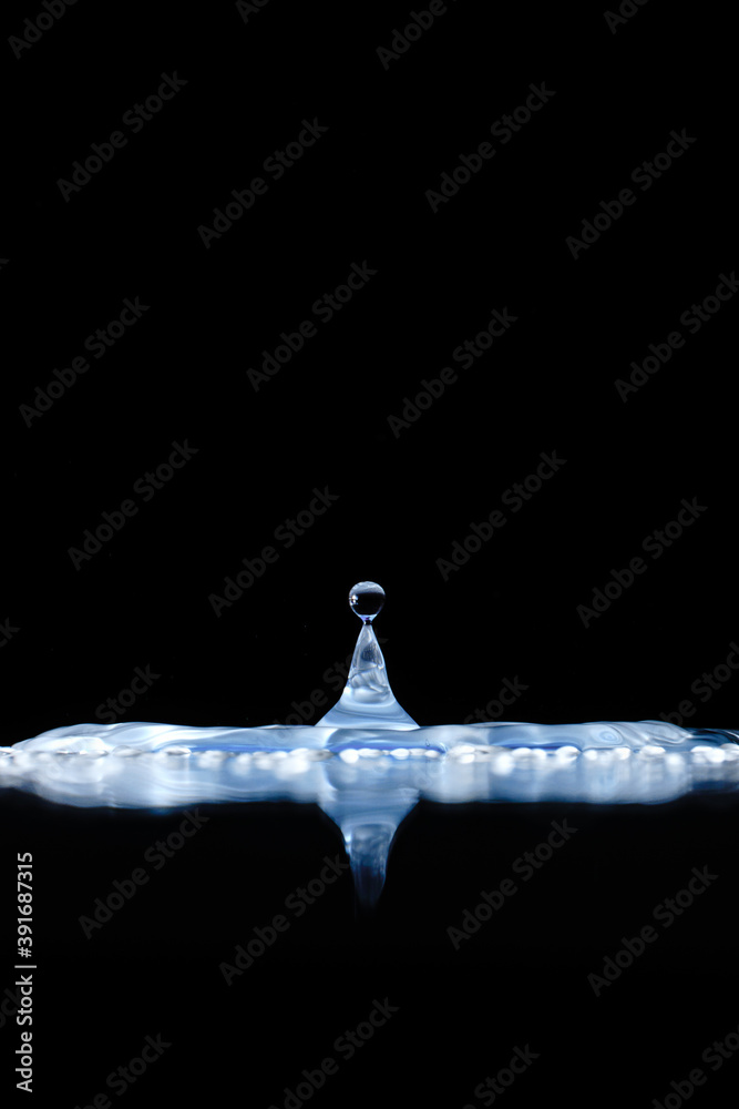 Poster Vertical closeup shot of clear water splash isolated on a dark background