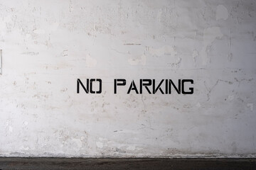 no parking sign on wall. Black Spray Paint Stencil No Parking Sign On Weathered Of White Concrete Wall With Peeling Paint, Cracks And Grunge, Abstract, Backgrounds, Textures. Stock Photograph.
