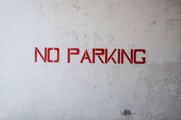 no parking sign on wall. Red Spray Paint Stencil No Parking Sign On Weathered Of White Concrete Wall With Peeling Paint, Cracks And Grunge, Abstract, Backgrounds, Textures. Stock Photograph.