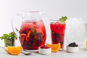 Glass and jug of red berry lemonade with orange