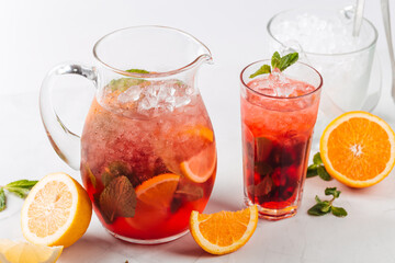 Side view on red berry lemonade in a jug and glass