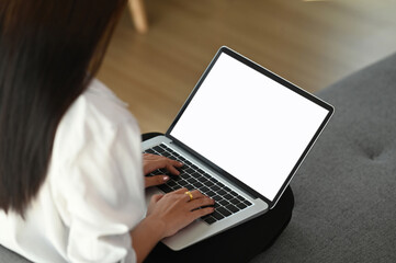 Rear view of girl sit relax on couch and using laptop browsing unlimited wireless internet at home.