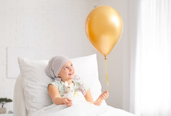 Little girl with golden balloon undergoing course of chemotherapy in clinic. Childhood cancer awareness concept - obrazy, fototapety, plakaty