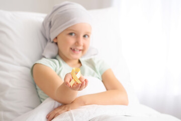 Obraz na płótnie Canvas Little girl with golden ribbon in clinic. Childhood cancer awareness concept