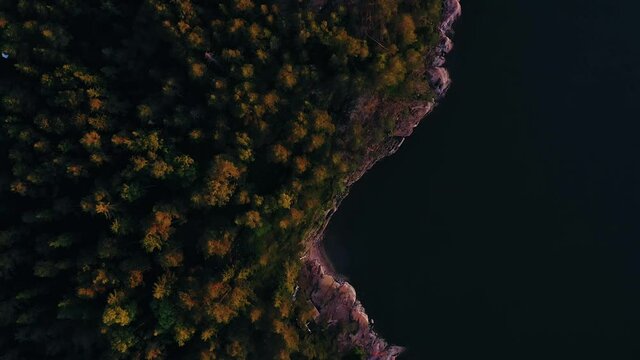 Aerial view above the coast of a island, in the archipelago, during a colorful, summer sunset, in Scandinavia - top down, drone shot