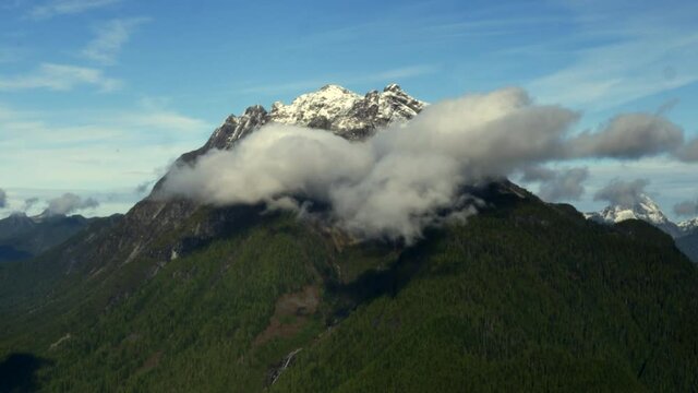 Beautiful Snow-Capped And Lush Green Mountain With Fluffy Clouds In BC, Canada - Aerial Drone Shot