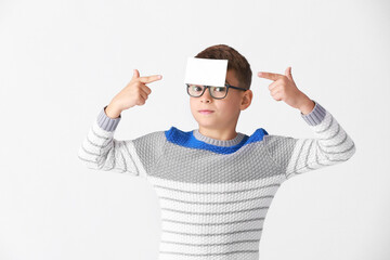 Naklejka premium Boy with blank note paper on his forehead against light background