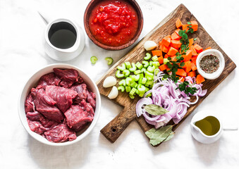 Ingredients for cooking beef in burgundy - beef fillet, tomato sauce, red wine, vegetables on a light background, top view