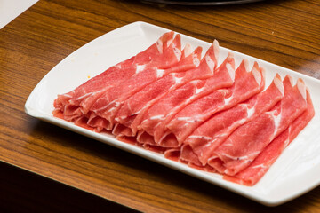 Thin sliced raw beef meat in a white plate for Shabu-shabu Hot Pot Japanese cuisine