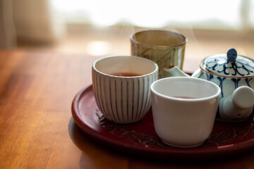 日の当たるテーブルに置かれた急須と入れたてのほうじ茶の入った湯飲み