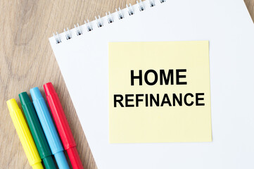 the inscription on the yellow sheet for notes text Home Refinance, which is attached to the notebook on the table.