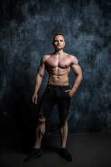 Handsome athletic man posing on black background.