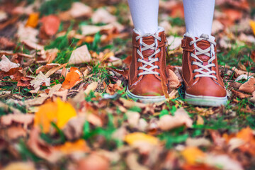 Children in the park with autumn leaves on shoes