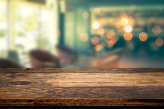 Empty wooden table with abstract blurry image of coffee shop or cafe restaurant in background for product showing and advertising.