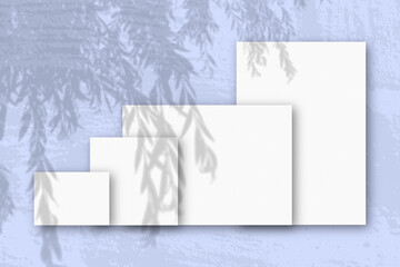 Several horizontal and vertical sheets of white textured paper against a blue wall background....