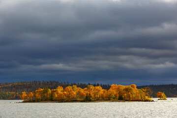 Clouds over an island in a lake in the mountainous part of the tundra in autumn.